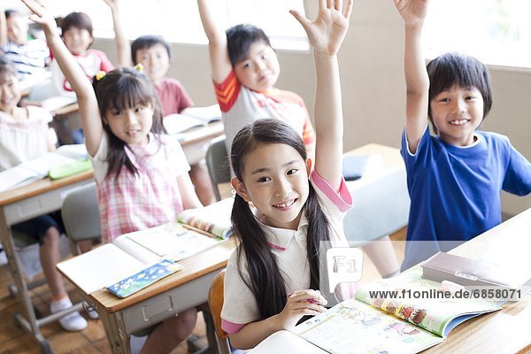 Schoolchildren Raising Hands in Classroom