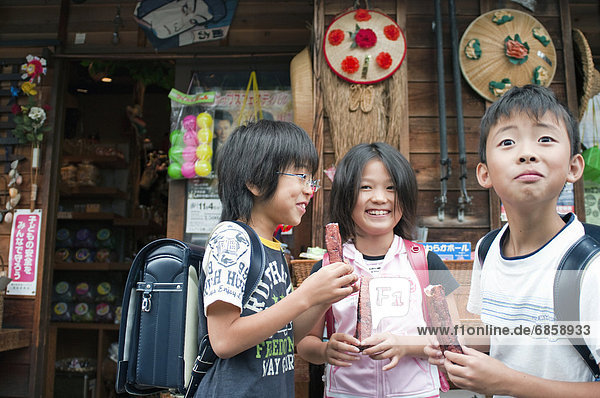 Kids in front of Dagashi-ya eating snacks  Japan