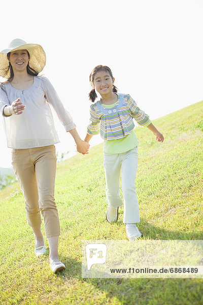 Mother and Daughter Walking Hand in Hand in Field