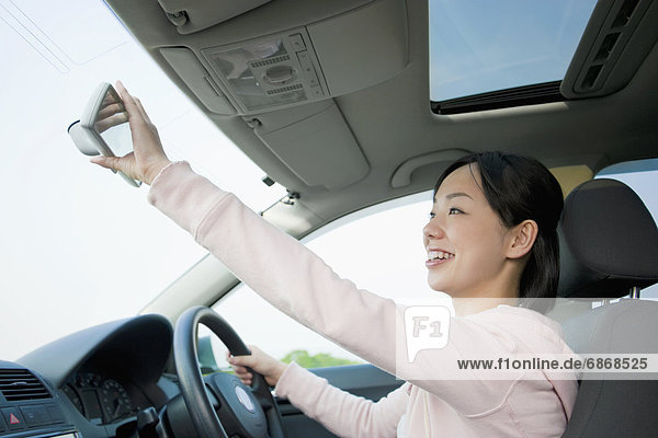 Young Woman Driving Car and Looking Into Rear Mirror