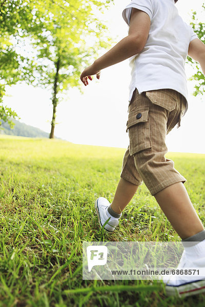Low Section View of Boy Walking on Grass