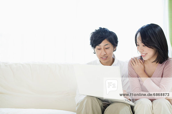 Young Couple Using Laptop on Sofa
