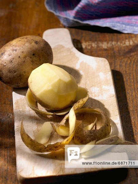 Potatoes  whole and peeled on a wooden board