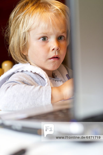 Blondes Mädchen schaut auf einen Laptop