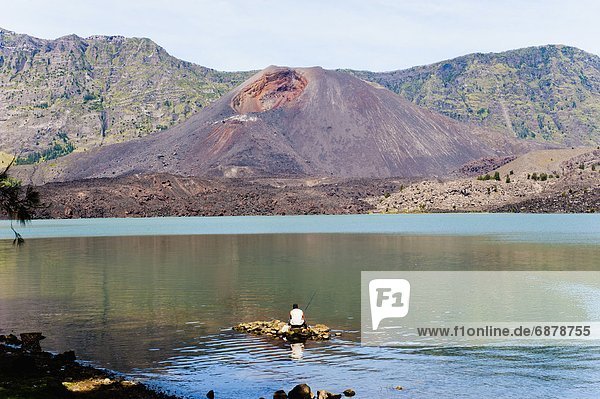 Man fishing in front of Mount Baru Jari  Segara Anak Lake at the bottom of Mount Rinjani volcano crater  Lombok  Indonesia  Southeast Asia  Asia