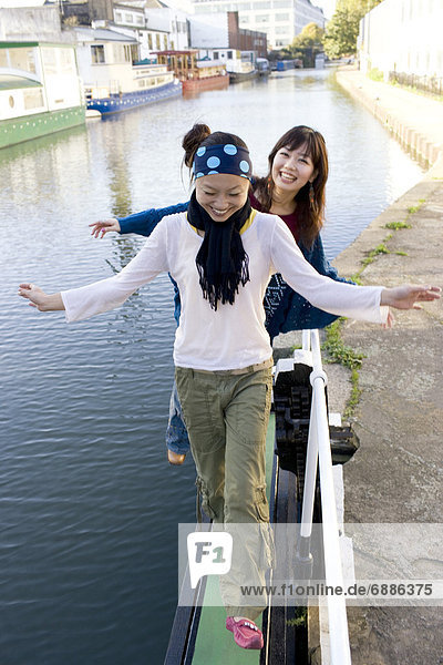 Two Young Women Balancing by Edge of River