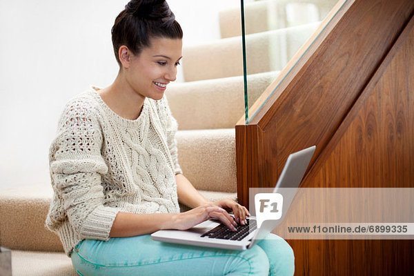 Junge Frau auf der Treppe sitzend mit Laptop