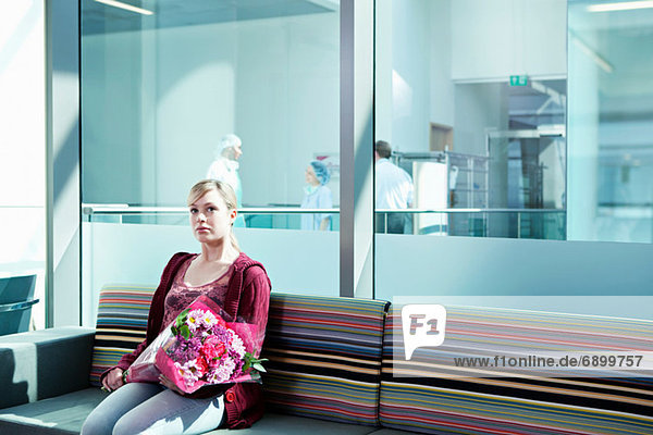Frau im Wartezimmer des Krankenhauses mit Blumenstrauß