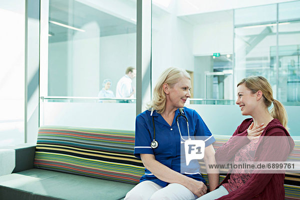 Krankenschwester im Gespräch mit Frau im Wartezimmer des Krankenhauses
