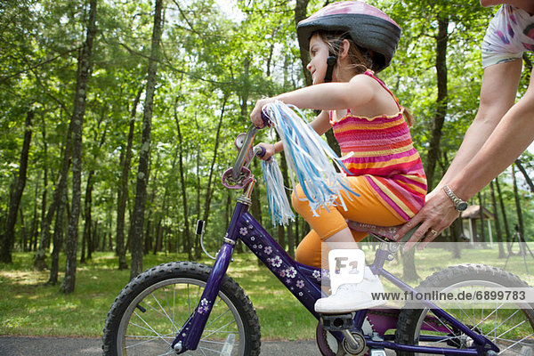 Mutter hilft Tochter beim Radfahren