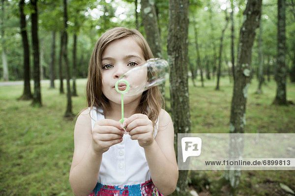 Mädchen bläst Blasen im Wald