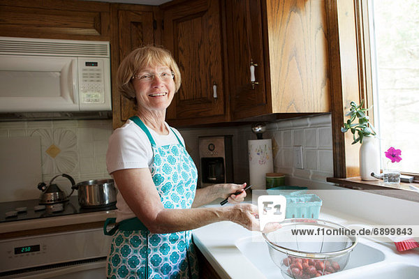 Frau bereitet Erdbeeren in der Küche zu