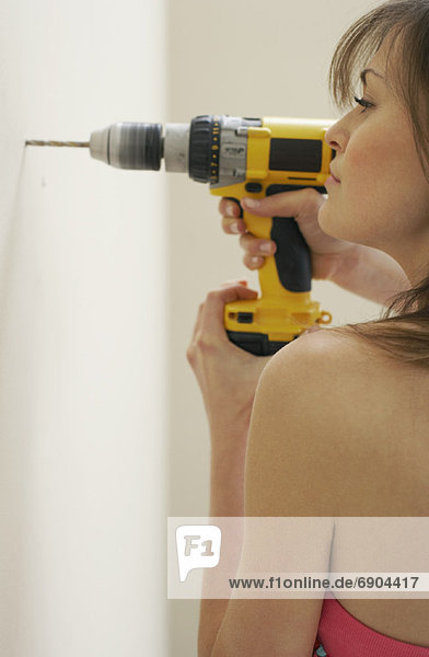 Woman Drilling Hole in Wall