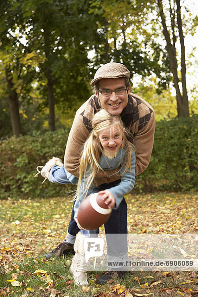 Portrait of Father and Daughter Playing American Football  in Autumn