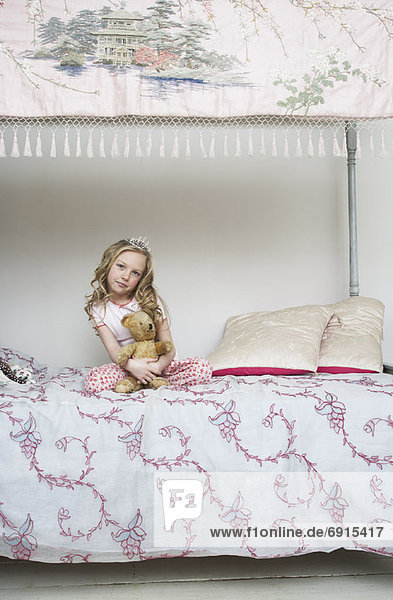 Girl Sitting on Bed  Holding Teddy Bear and Wearing Tiara