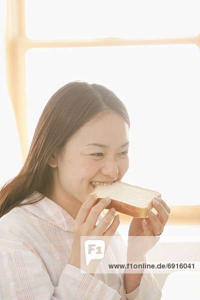 Young Woman Eating Slice of Bread
