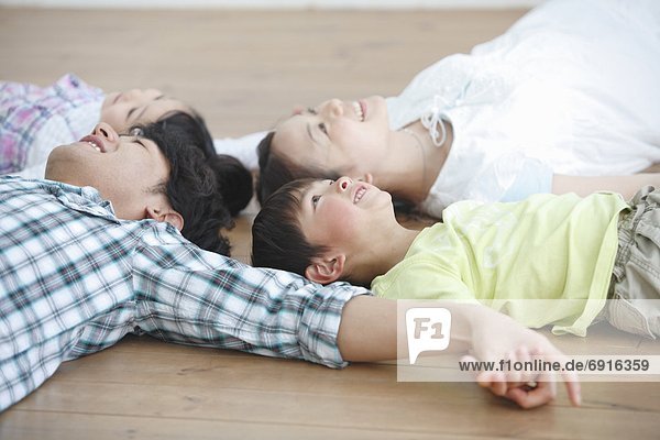 Family of Four Lying on Floor and Holding Hands