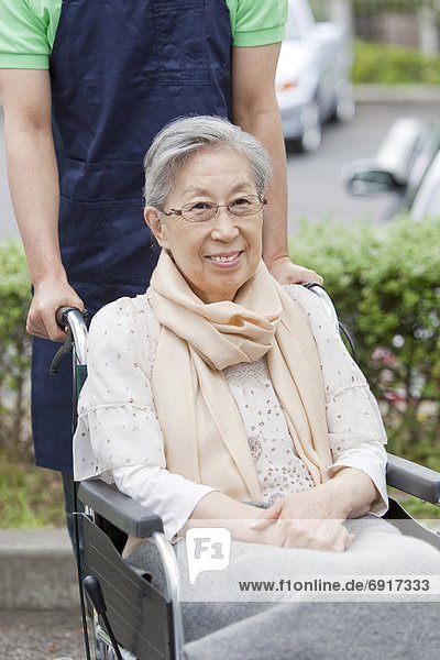 Healthcare worker pushing senior woman in wheelchair  Kanagawa Prefecture  Honshu  Japan