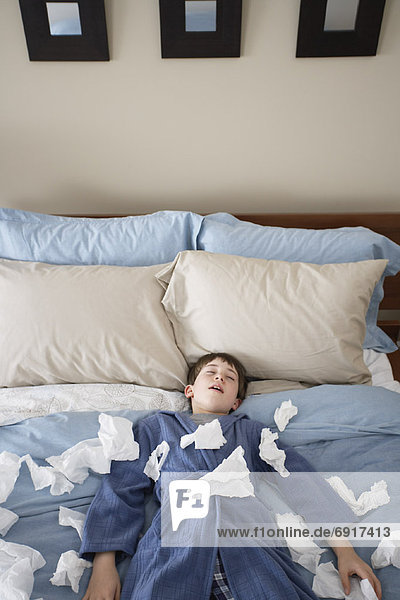 Boy Lying on Bed  Surrounded by Tissues