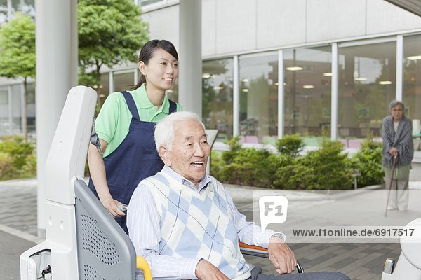 Healthcare worker helping senior man in wheelchair getting into a van  Kanagawa Prefecture  Honshu  Japan