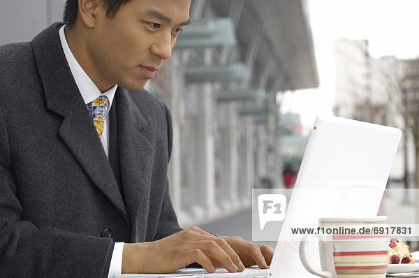 Businessman Using Laptop Computer At Cafe