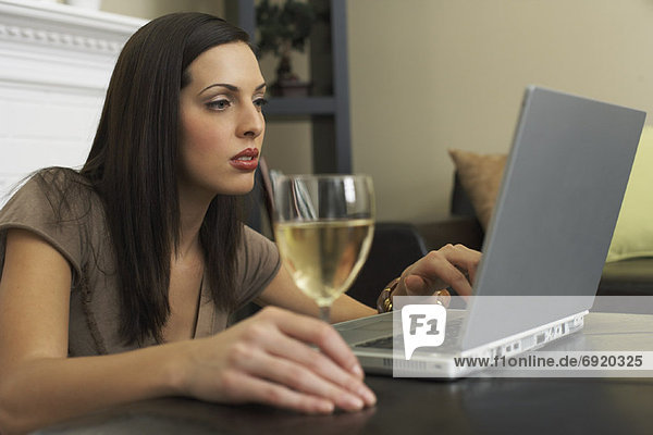 Woman Using Laptop Computer  Drinking Glass of Wine