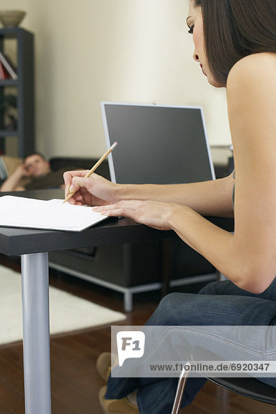 woman Working at Computer and Man Napping on Couch