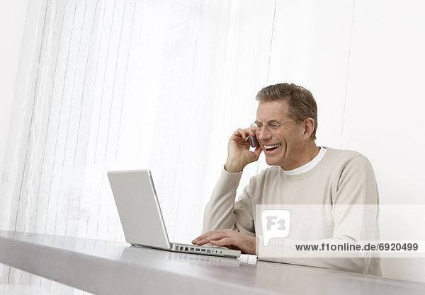 Man Using Laptop and Cell Phone