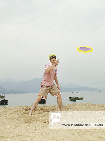 Mann spielen Frisbee am Strand