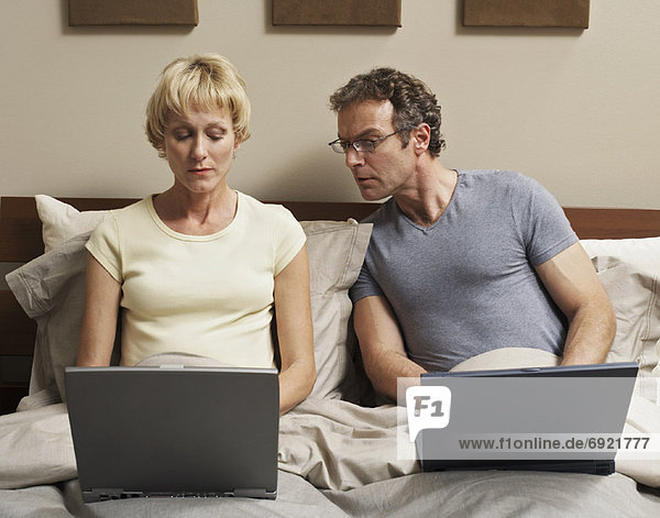Couple Using Laptop Computers in Bed