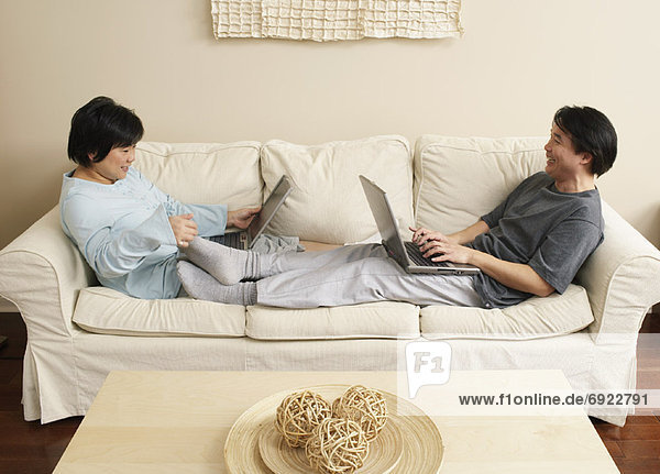 Couple Using Laptops on Sofa
