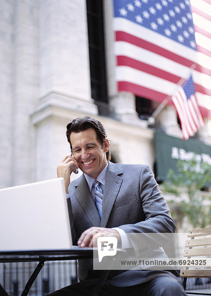 Businessman with Laptop Computer by American Flag