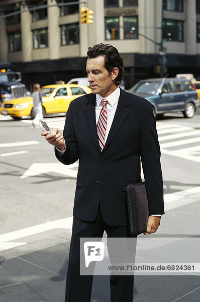 Businessman using Cellular Phone on Sidewalk