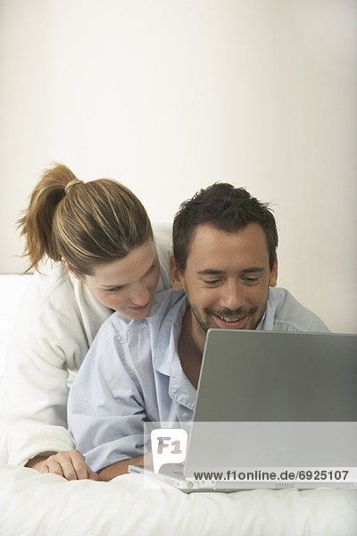 Couple in Bed  Using Laptop