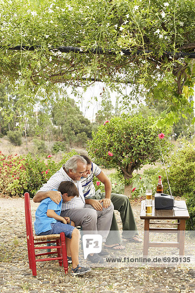 Grandfather  Father and Son Watching Television in Backyard