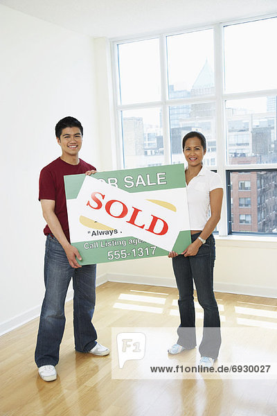 Couple Holding Sold Sign