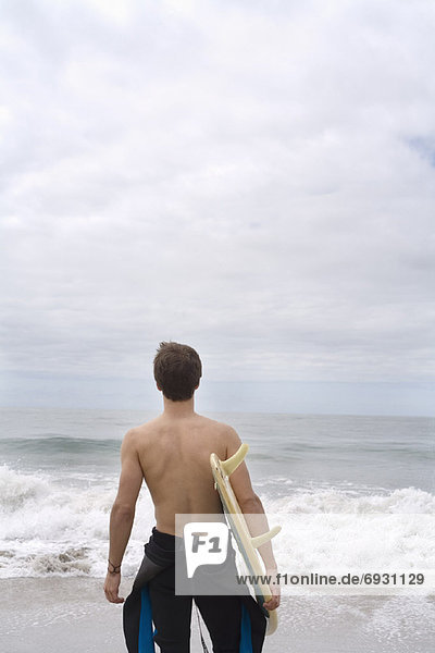 Mann  hält Surfboard