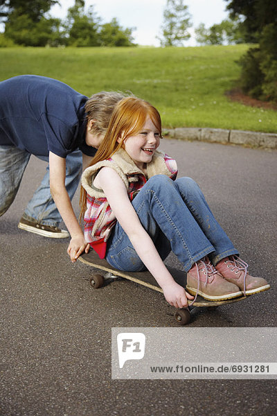 Boy Pushing Girl on Skateboard