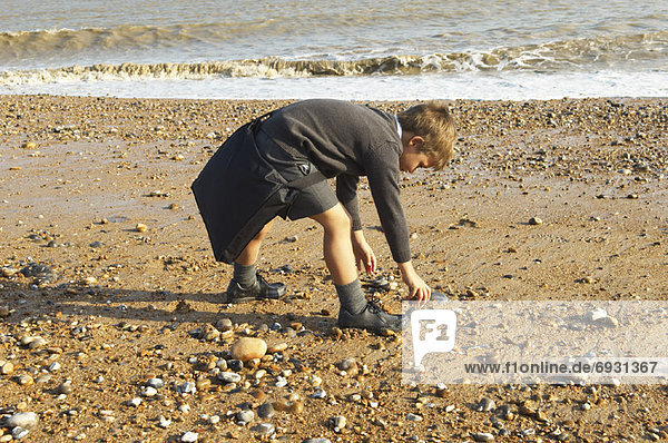 Boy Picking Up Rocks at the Beach