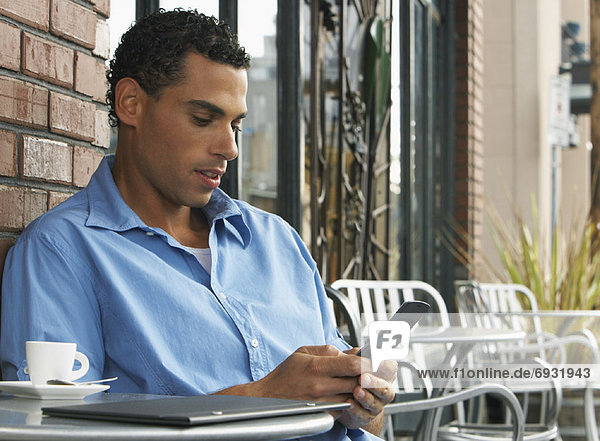 Man sitting at Cafe Table and Using Cellular Phone