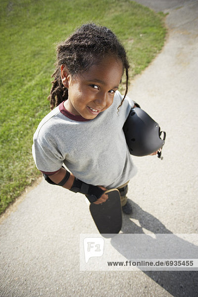 Boy Holding Skateboard and Helmet