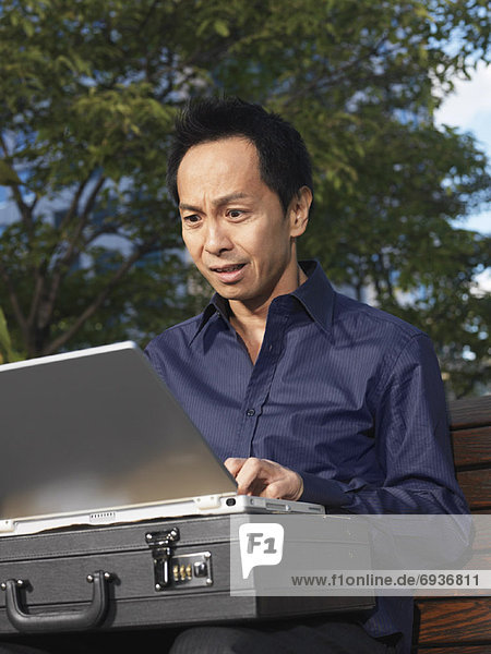 Man on Park Bench Using Laptop Computer