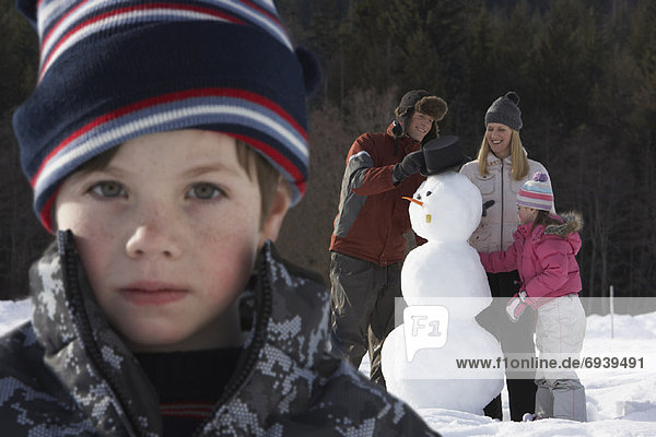 Portrait of Boy  Family Making Snowman in Background