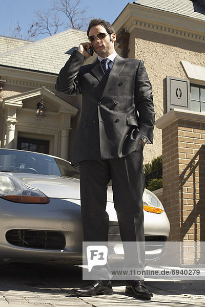 Businessman with Cellular Phone in Driveway