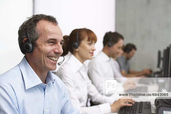 Business People Working at Computers with Headsets