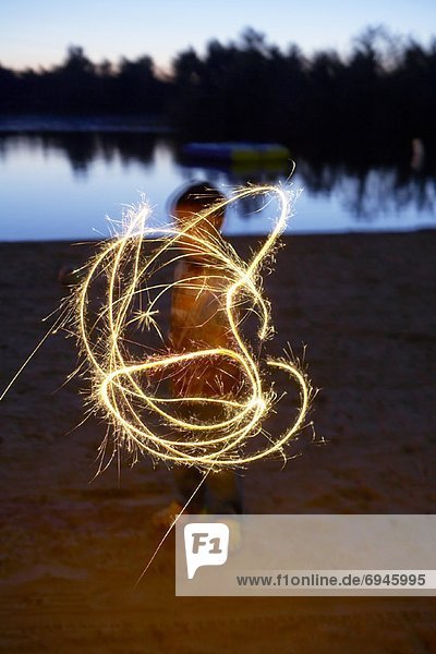 Child Playing with Sparkler by Lake
