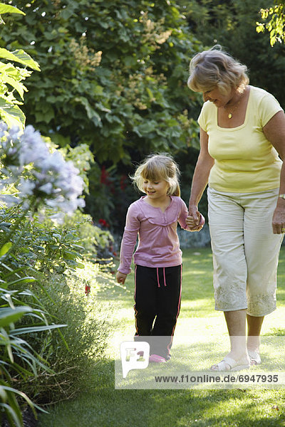 Grandmother and Granddaughter Walking in Garden
