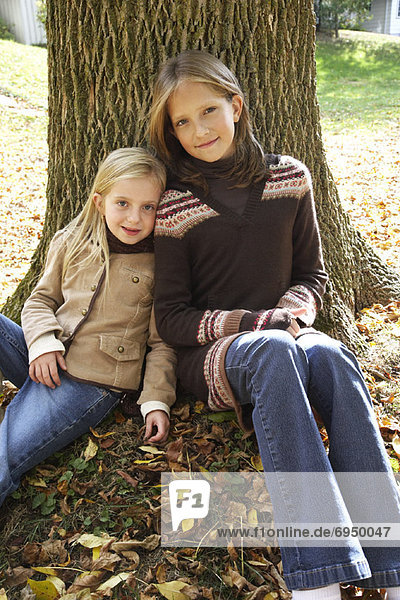 Portrait of Girls Sitting in Front of Tree  in Autumn