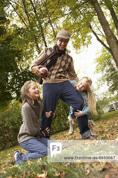 Portrait of Father and Daughters Playing American Football  in Autumn