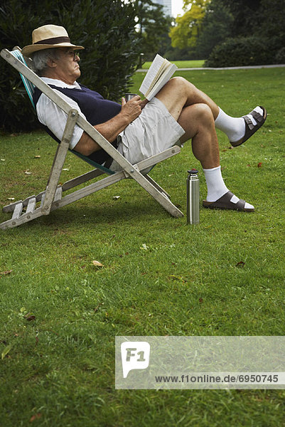 Man Sitting in Lawn Chair  Reading Book